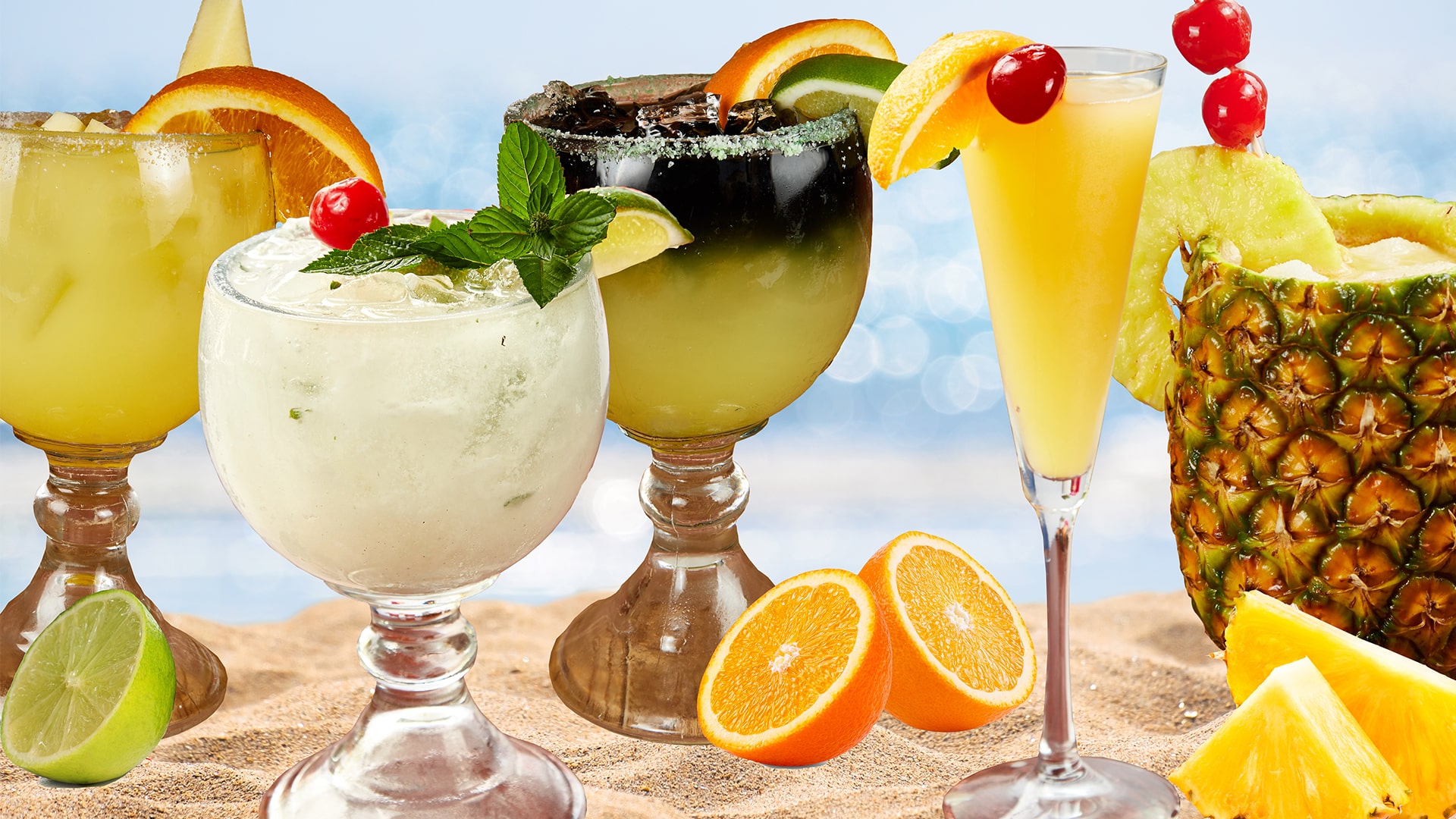 A row of margaritas and frozen cocktails in wide bowl glasses with orange, lime, pineapple and cherry garnishes
